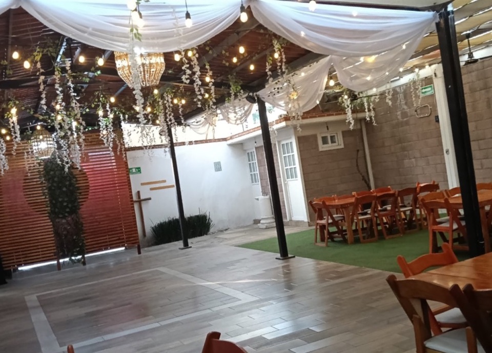 El salón de día: pista, techo con luces y flores, y mesas sobre el pasto