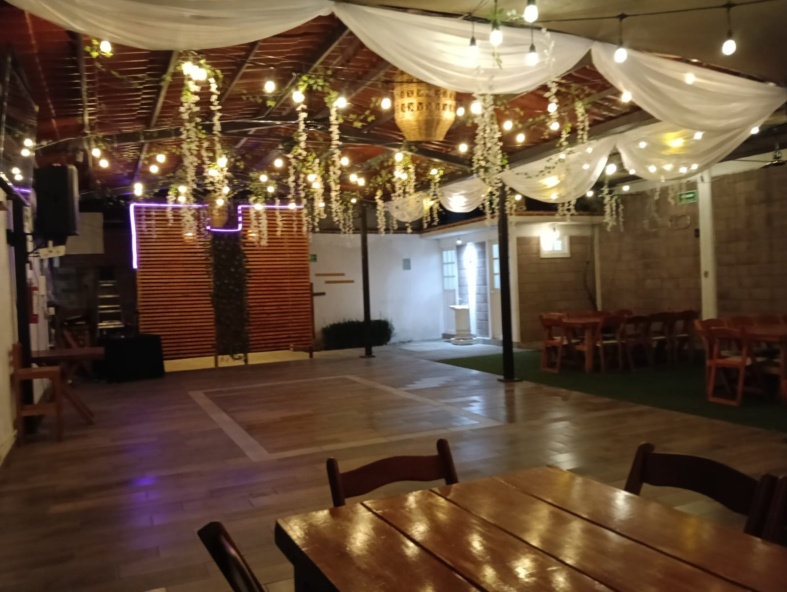 La pista de noche, con luces colgantes, telas y flores en el techo